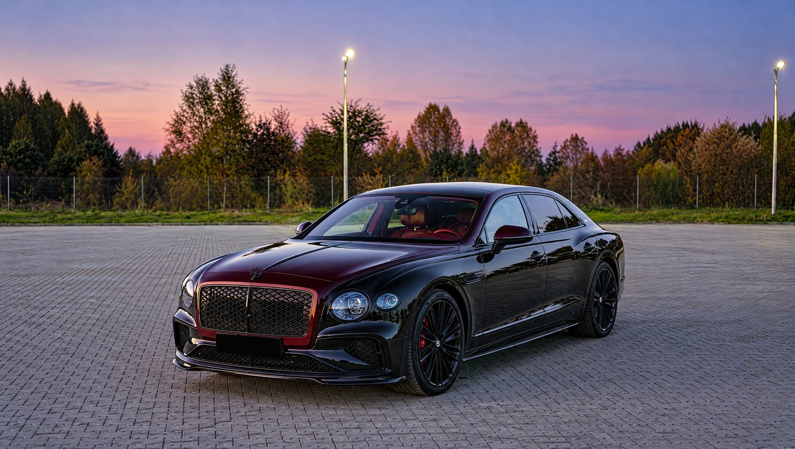 Bentley Flying Spur w kolorze czarnym i burgundowym na placu MAGNUS AUTOZONE o zmierzchu